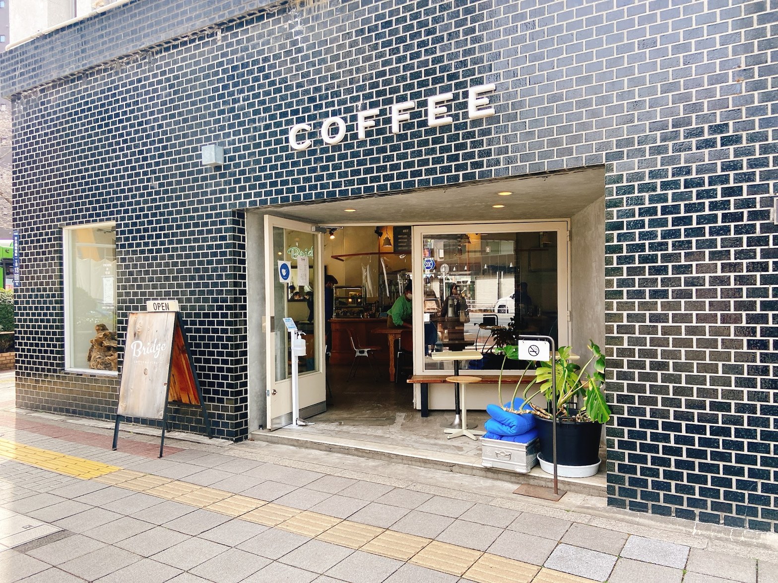 黒タイル張りのファサードに白抜き「COFFEE」の文字、木製のBridgeサインボードとOPENの看板が並ぶイーグルビル1F入口